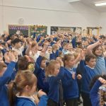 Group of students with their arms in the air.